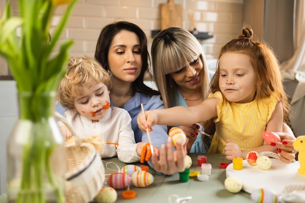 Felices madres y sus hijos decorando huevos de Pascua