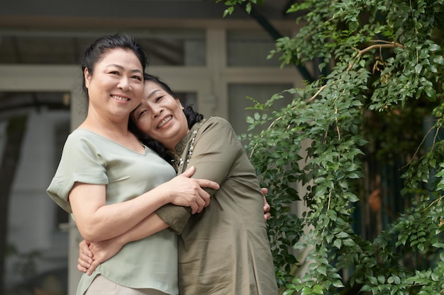 Felices mejores amigas senior abrazándose para expresar emociones positivas