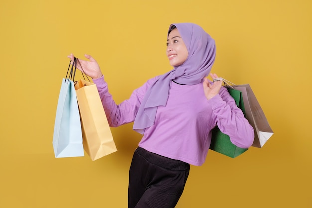 Felices las mujeres jóvenes adictas a las compras mostrando bolsas, vistiendo camiseta púrpura