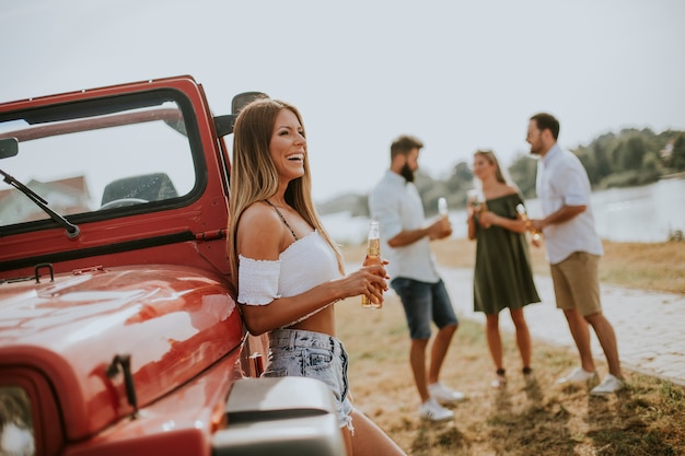 Felices mujeres jóvenes beben sidra de la botella en el auto convertible