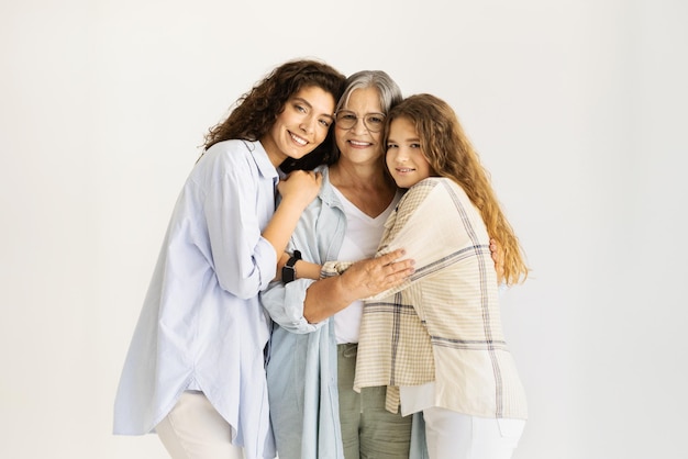 Felices mujeres maduras y adolescentes caucásicas mayores abrazándose disfrutan del amor en el fondo de la pared blanca