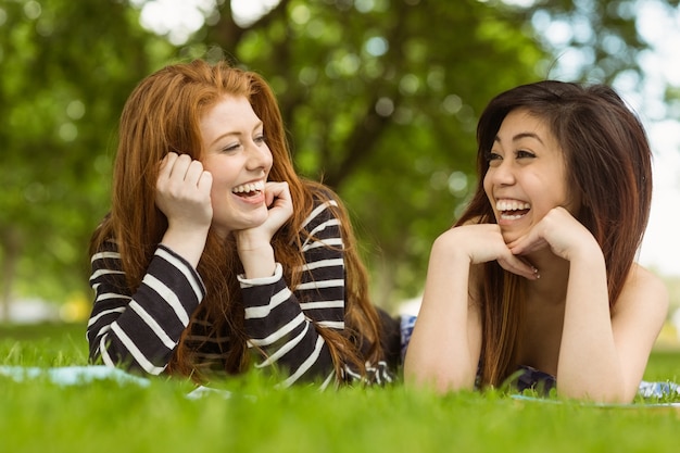 Felices mujeres relajadas tumbado en la hierba en el parque