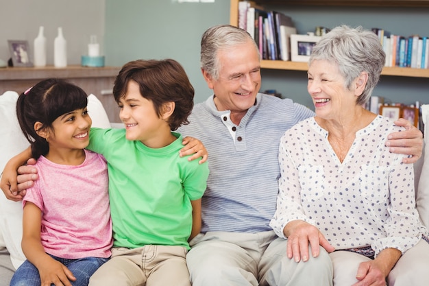 Felices nietos con abuelos en el sofá en casa