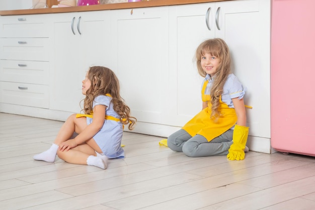 Felices niñas en edad preescolar mojadas limpiando la cocina.