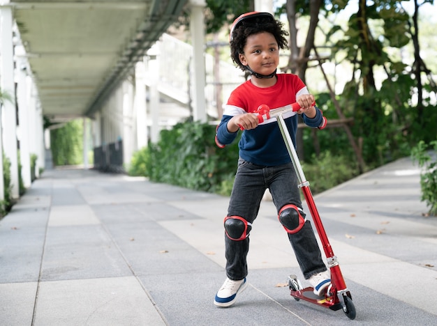 Felices los niños afroamericanos afroamericanos juegan scooter