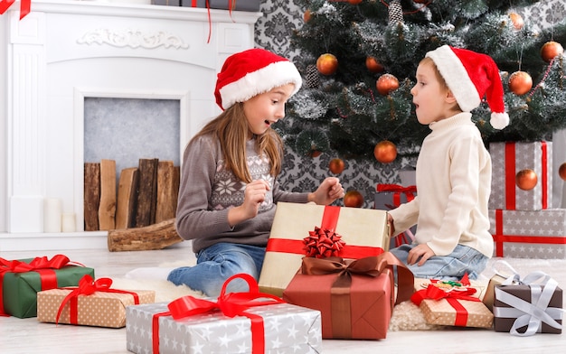 Felices los niños emocionados desenvolver la caja de regalo de Navidad en la mañana de vacaciones