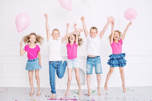 Felices los niños lindos hermosos sonríen en la fiesta con globos y confeti juntos