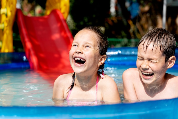 Felices niños sanos nadan en la piscina en verano y se ríen