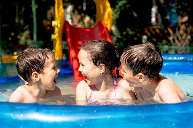 Felices niños sanos nadan en la piscina en verano y se ríen