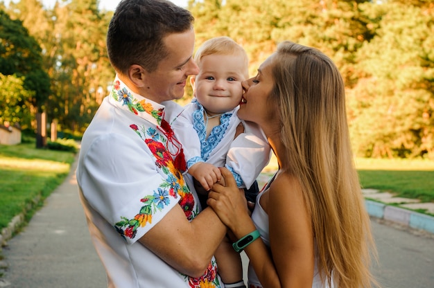 Felices padres con un bebé vestido con la camisa bordada