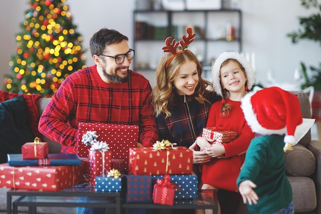Felices padres de familia e hijos abren regalos en la mañana de Navidad