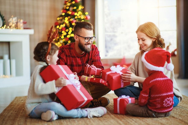 Felices padres de familia e hijos abren regalos en la mañana de Navidad