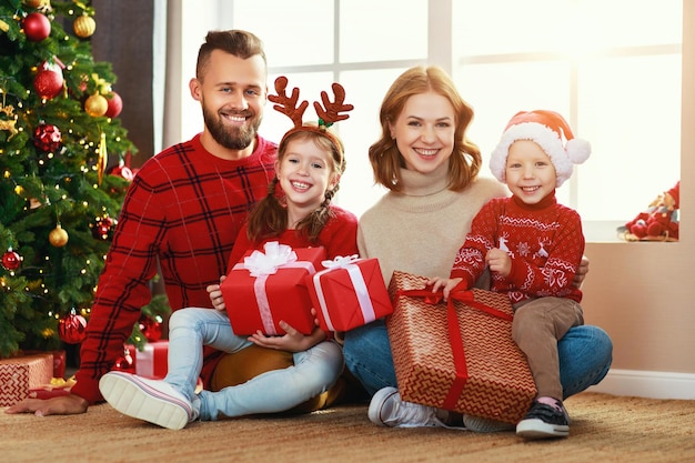 Felices padres de familia e hijos abren regalos en la mañana de Navidad