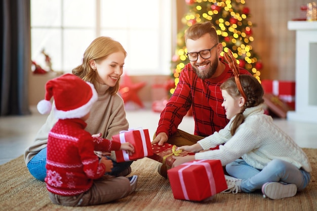 Felices padres de familia e hijos abren regalos en la mañana de Navidad