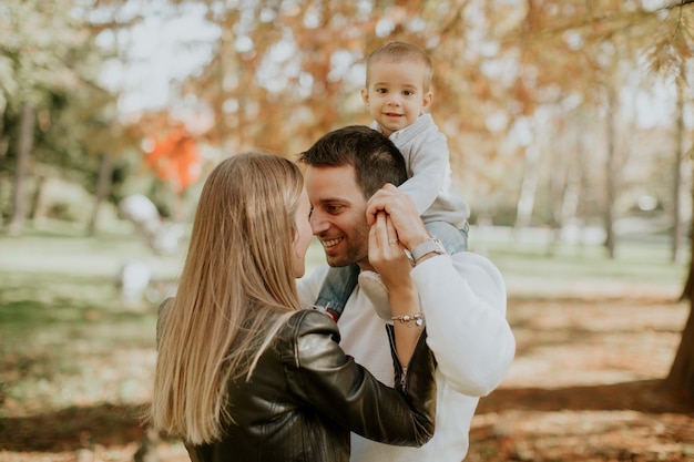 Felices padres jóvenes con bebé en el parque de otoño