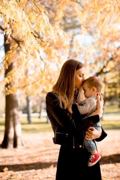 Felices padres jóvenes con bebé en el parque de otoño