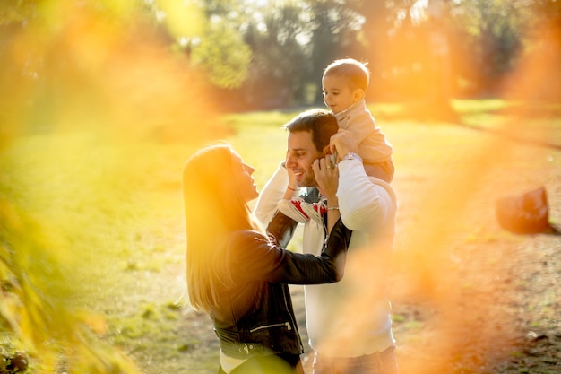 Felices padres jóvenes con bebé en el parque de otoño