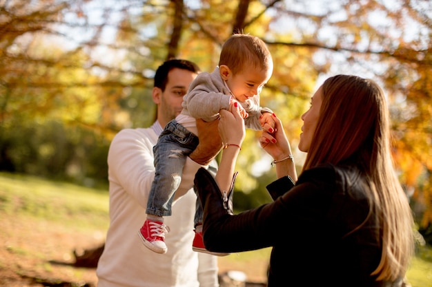 Felices padres jóvenes con bebé en el parque de otoño