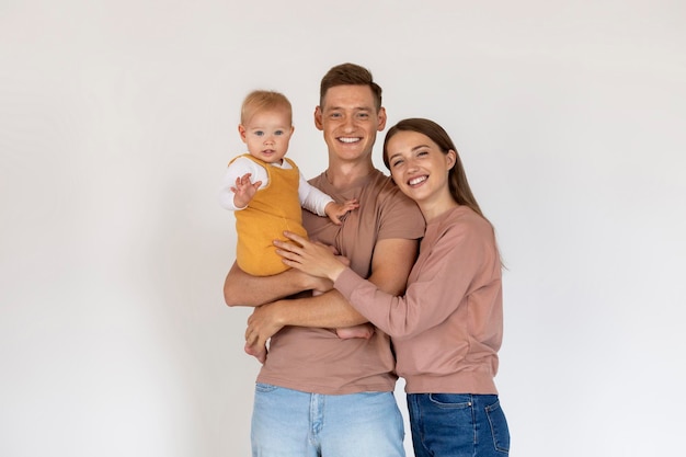 Foto felices padres jóvenes sosteniendo a su lindo hijo pequeño y sonriendo a la cámara