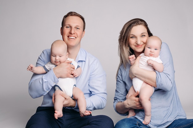 Felices padres jóvenes con sus gemelos sonriendo a la cámara.