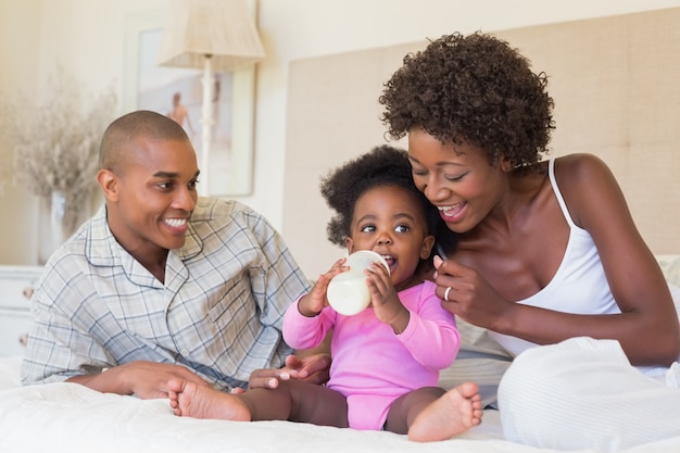 Felices padres con niña en su cama