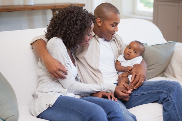 Felices padres pasar tiempo con el bebé en el sofá