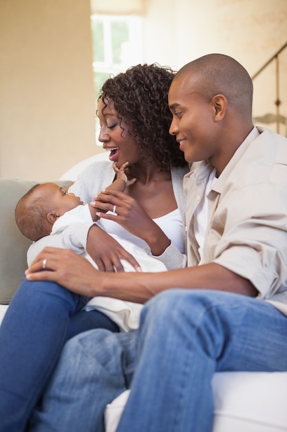 Felices padres pasar tiempo con el bebé en el sofá