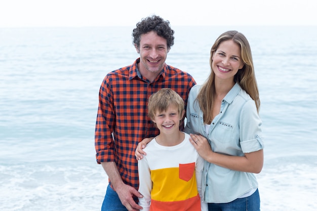 Felices padres de pie con hijo por mar