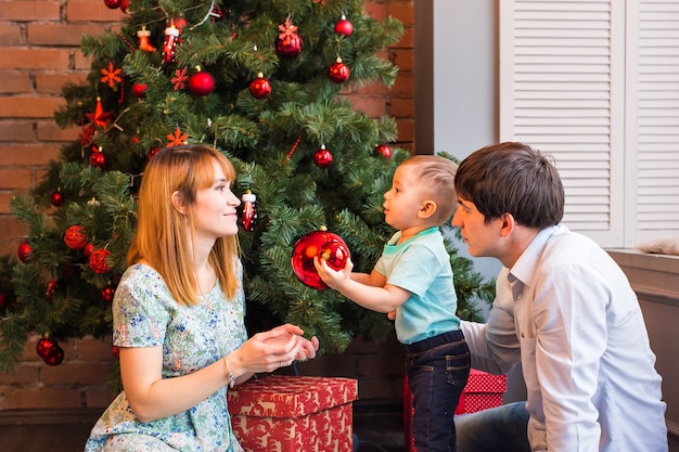 Felices padres sonrientes y el niño en casa celebrando la Navidad