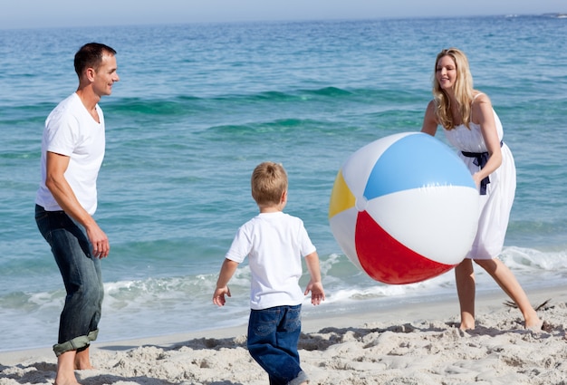 Felices padres y su hijo jugando con una pelota