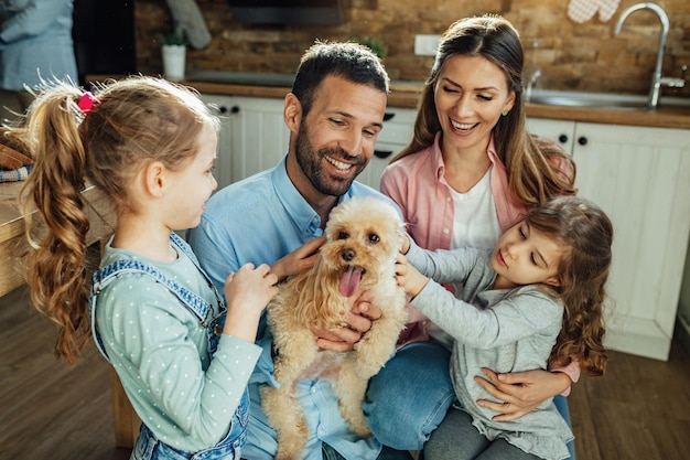 Foto felices padres y sus hijas divirtiéndose con un perro en casa