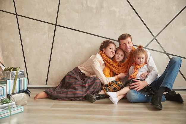 Felices padres con sus hijas sentadas en el suelo en un apartamento nuevo