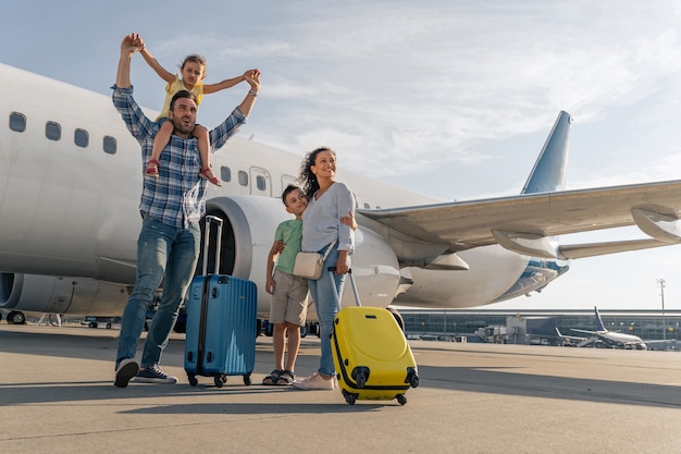 Felices padres y sus hijos esperando viajar juntos.