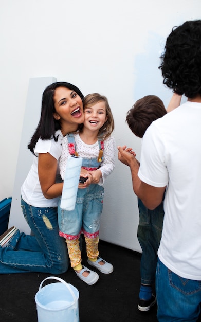 Felices padres con sus hijos pintando una habitación