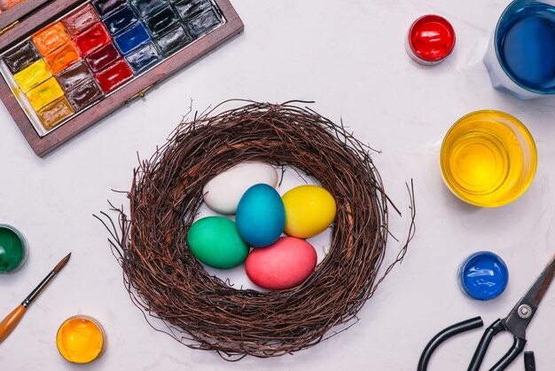 ¡Felices Pascuas! Amigos pintando huevos de Pascua en la mesa.