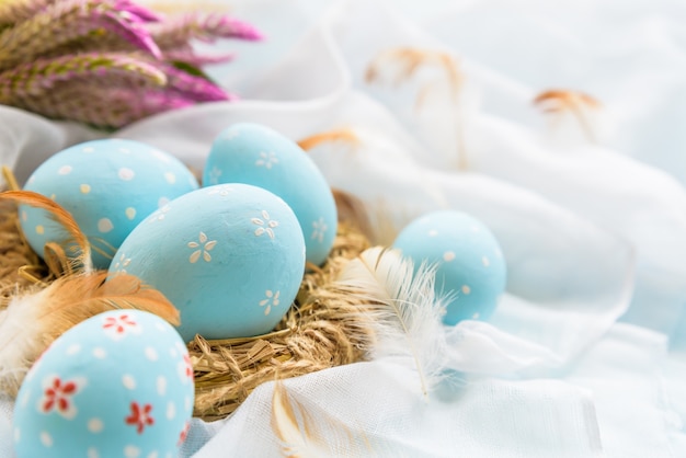 ¡Felices Pascuas! Colorido de los huevos de Pascua con la flor en el fondo blanco de la gasa.