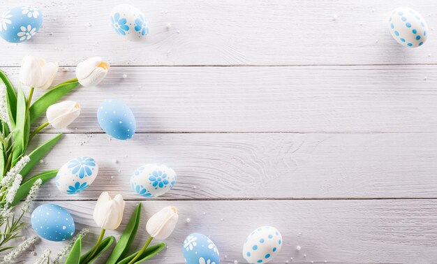 Felices Pascuas coloridos huevos de Pascua y flores sobre fondo blanco de madera