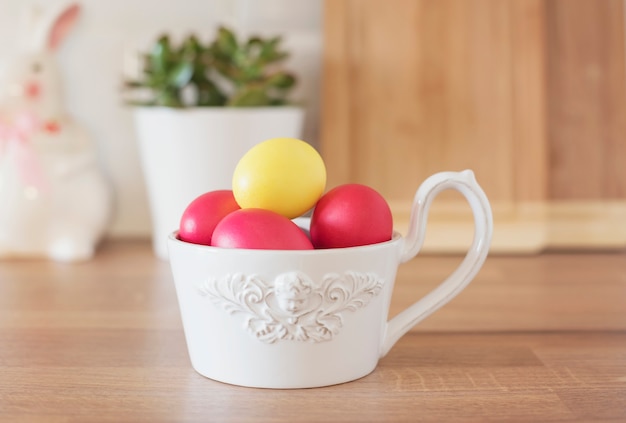 ¡Felices Pascuas! Coloridos huevos de Pascua en un tazón blanco, conejo, suculenta en la encimera de la cocina, de cerca. Utensilios De Cocina En La Cocina Moderna Interior.