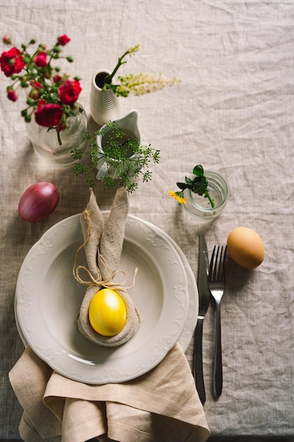 Felices Pascuas Elegantes huevos de Pascua en una servilleta con flores de primavera sobre fondo blanco de madera Ajuste de la tabla El concepto de unas felices vacaciones de Pascua