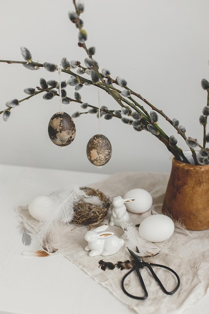 Felices Pascuas Huevos naturales figuritas de conejito plumas nido ramas de sauce en jarrón sobre mesa
