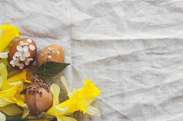 Felices Pascuas Huevos de Pascua decorados con flores secas sobre lino rústico con narcisos planos