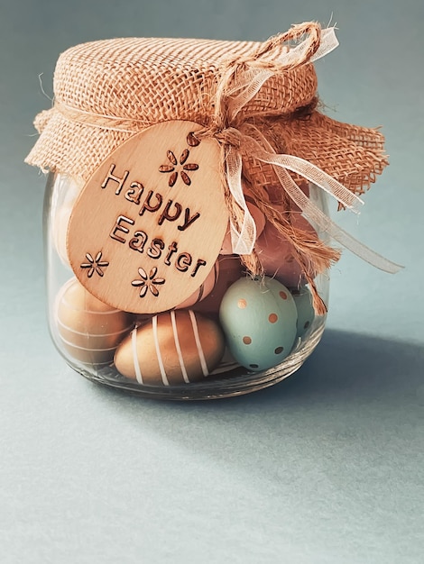 Felices Pascuas Huevos de Pascua pintados de colores en tarro de cristal sobre fondo azul Religión cristiana y concepto de vacaciones