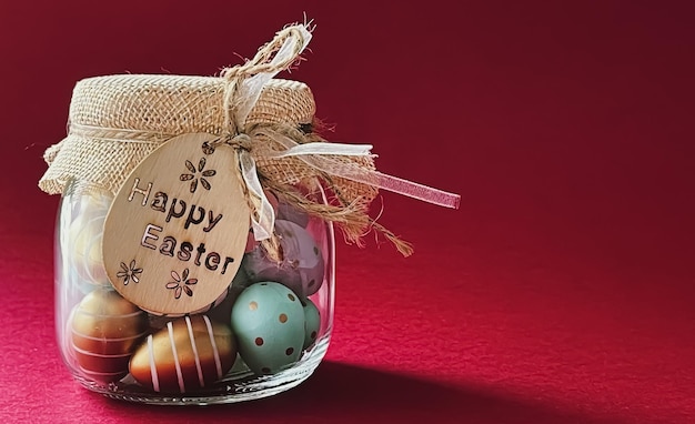 Felices Pascuas Huevos de Pascua pintados de colores en tarro de cristal sobre fondo rojo Religión cristiana y concepto de vacaciones