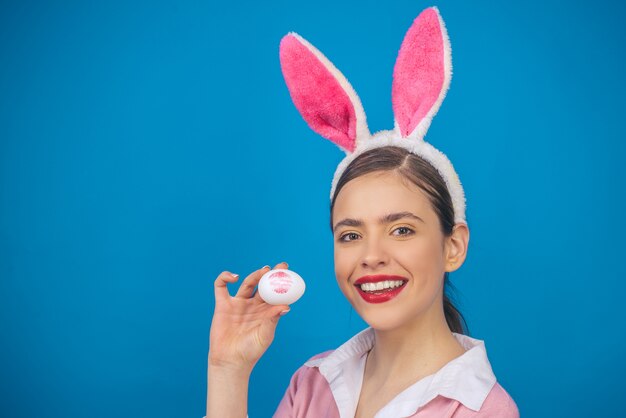 Felices Pascuas. Labios y Pascua, Impresión de beso de lápiz labial en huevo de Pascua. Mujer joven en orejas de conejo conejo