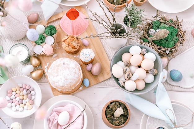 Felices pascuas y vacaciones de primavera tiempo festivo paisaje de mesa decoración cena tradicional comida huevos de pascua y pasteles horneados en la mesa en casa ramita de sauce pop pálido color azul pastel y rosa vista superior