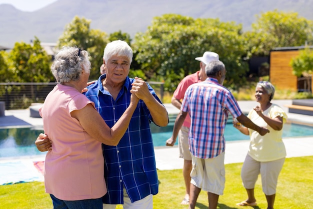 Felices personas mayores diversas bailando juntas y sonriendo en el jardín