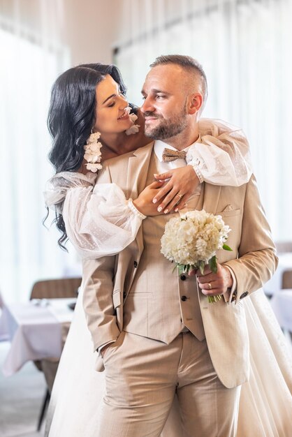 Felices recién casados abrazándose y besándose después de la ceremonia de la boda