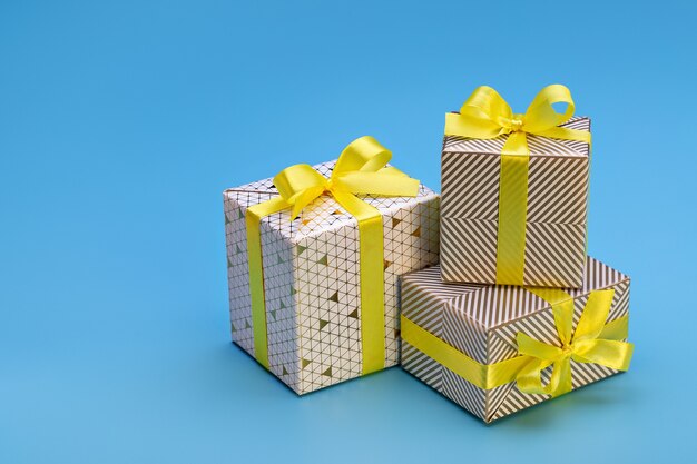 Felices vacaciones. Cajas de regalo con patrones, cinta amarilla con lazo sobre fondo azul. Estado de ánimo de año nuevo y Navidad.
