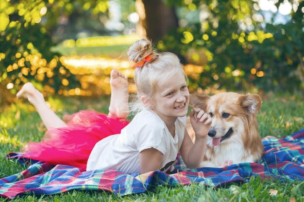 Felices vacaciones divertidas - hermosa chica rubia y corgi mullido en el césped en un día soleado de verano