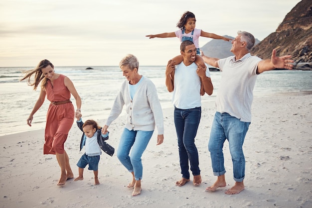 Felices vacaciones en familia y paseo por la playa para disfrutar de un tiempo de unión de calidad juntos al aire libre Madre, padre y abuelos con niños jugando con una sonrisa de felicidad por un viaje familiar junto al océano